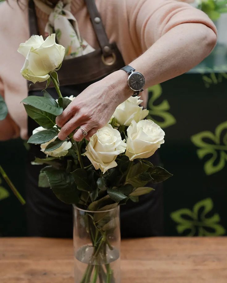 Person caring for fresh flowers in a vase to keep flowers fresh and healthy.
